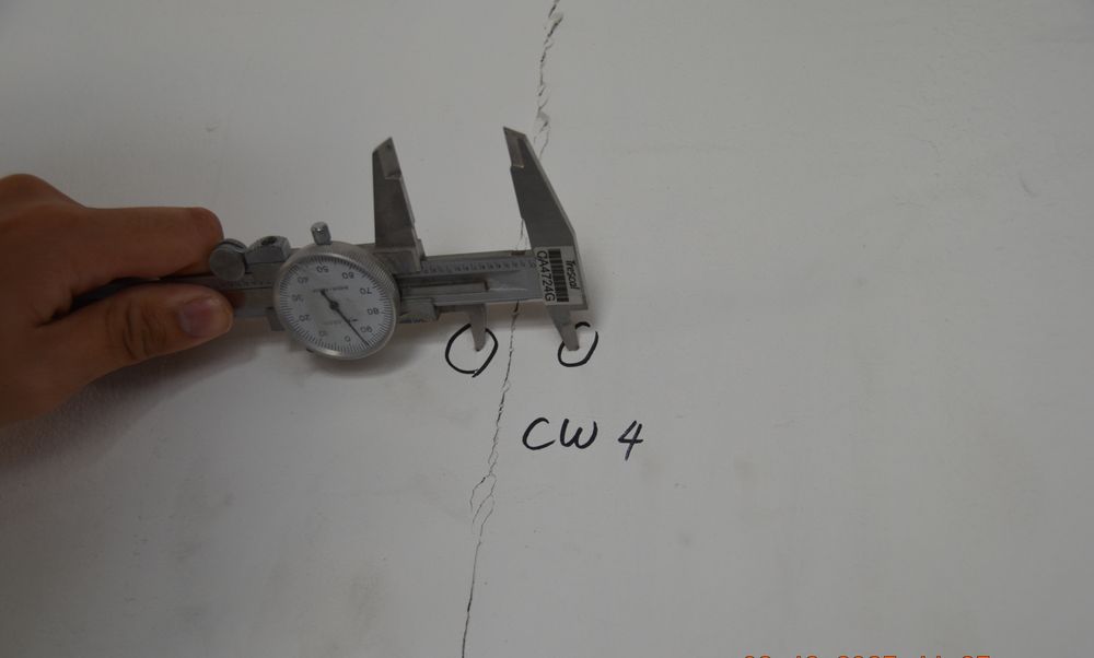 Dial caliper measuring crack width on a wall