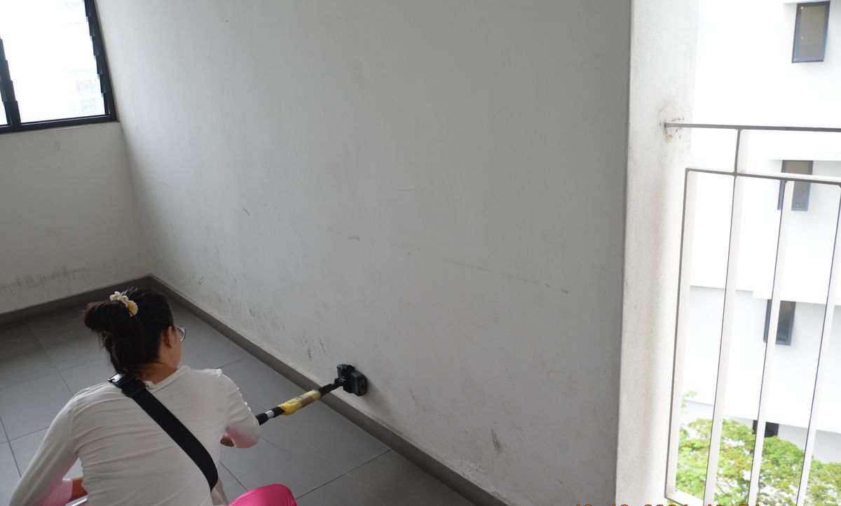 Surveyor testing walls with an extended moisture probe